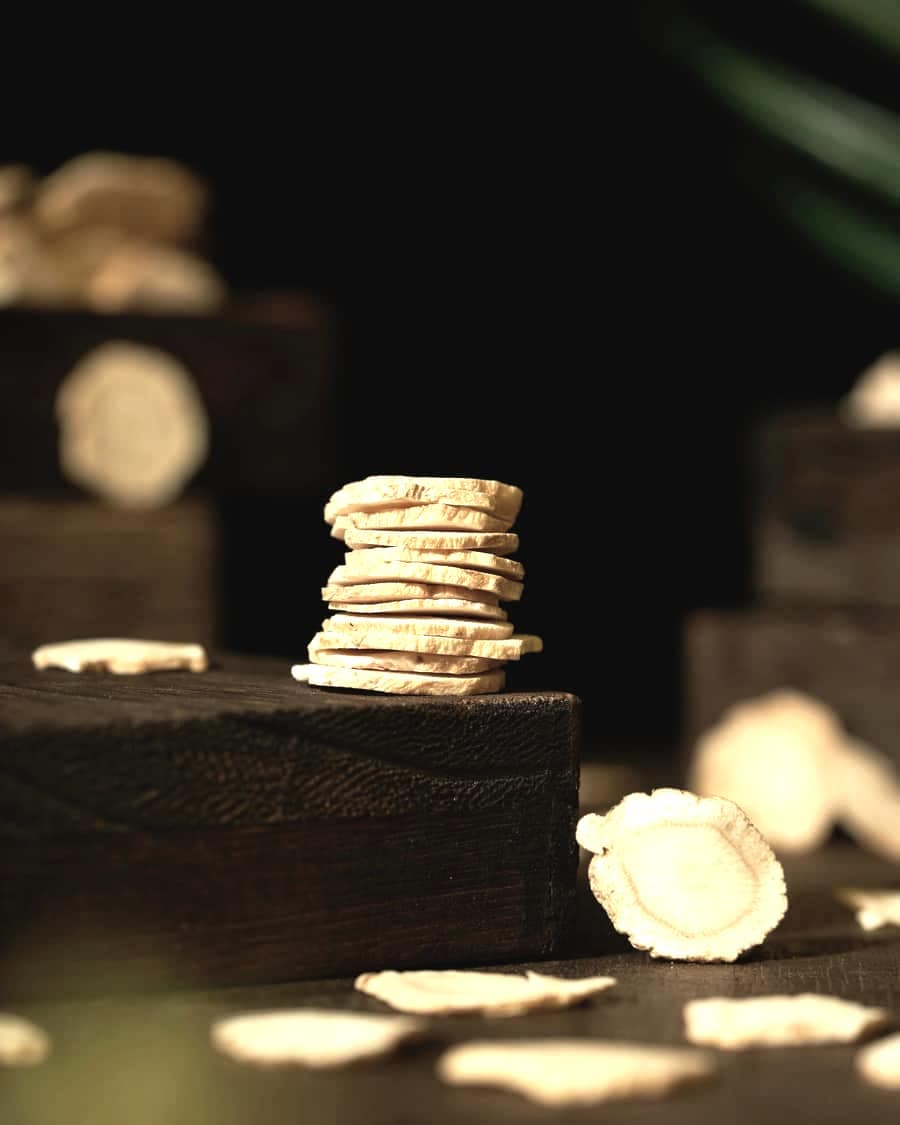 A stack of dried ginger slices on a dark wooden block