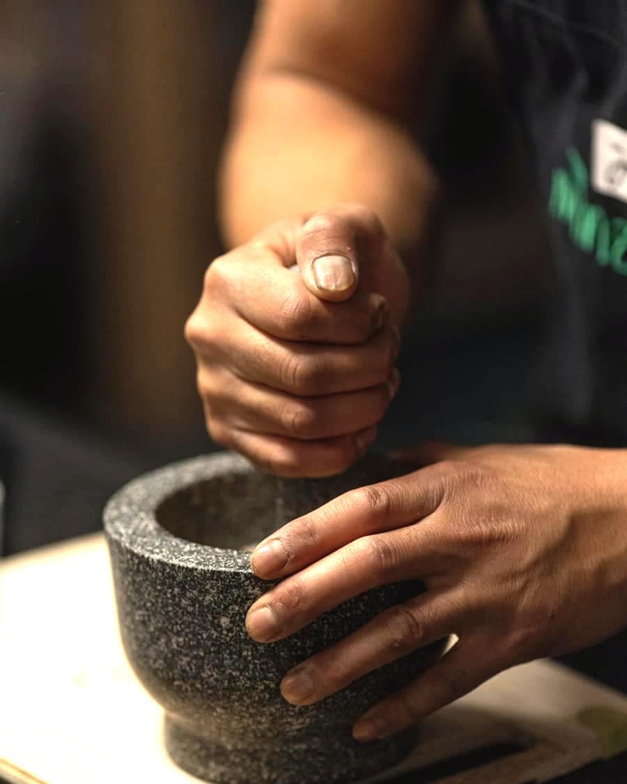 Hands working a stone mortar and pestle