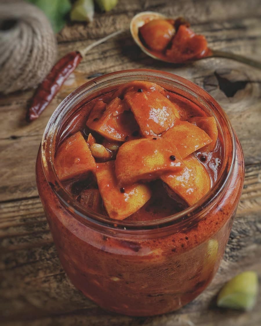 Mango pickle in a glass jar on a wooden table