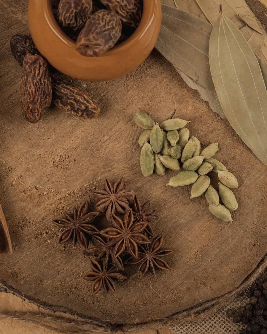 Cardamom, star anise and bay leaves arranged on a wooden board