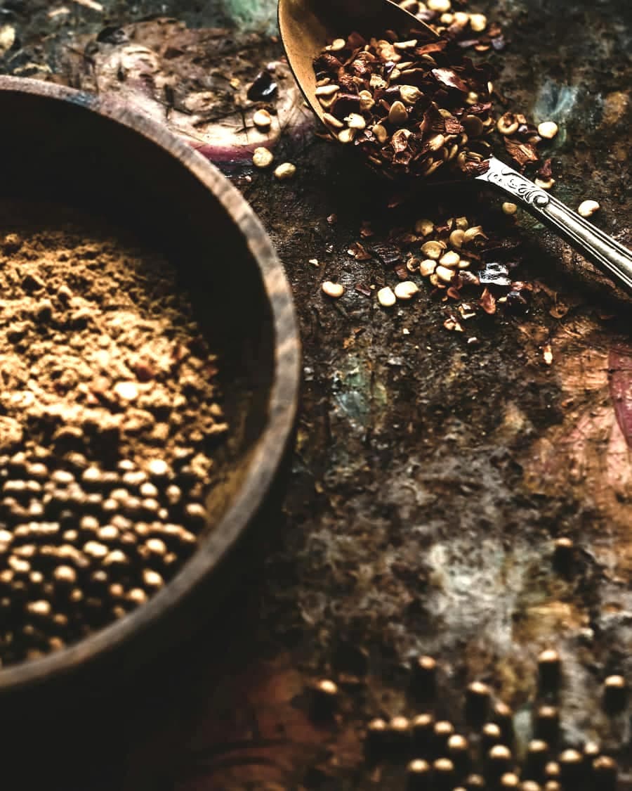 Chilli flakes and ground spice in a dark pan with a spoon