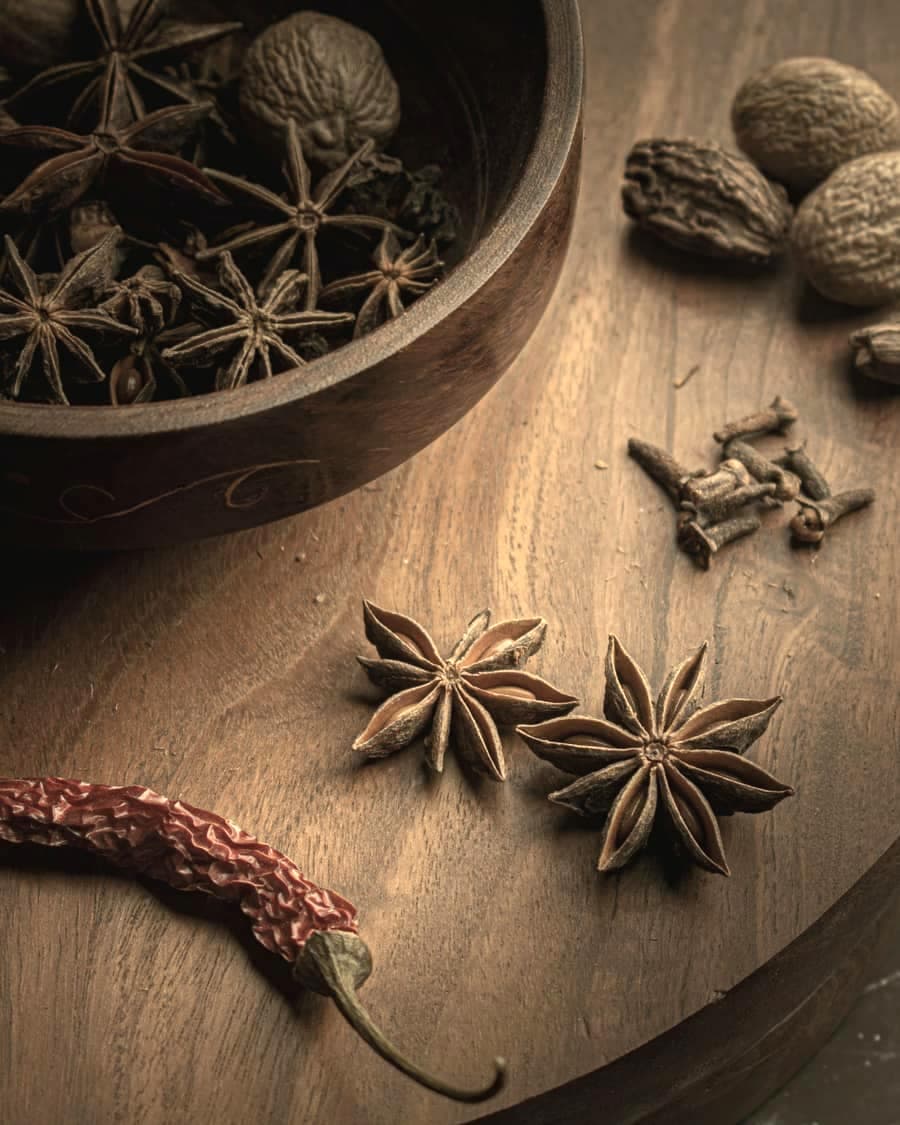 Star anise, nutmeg and a dried chilli on dark wood