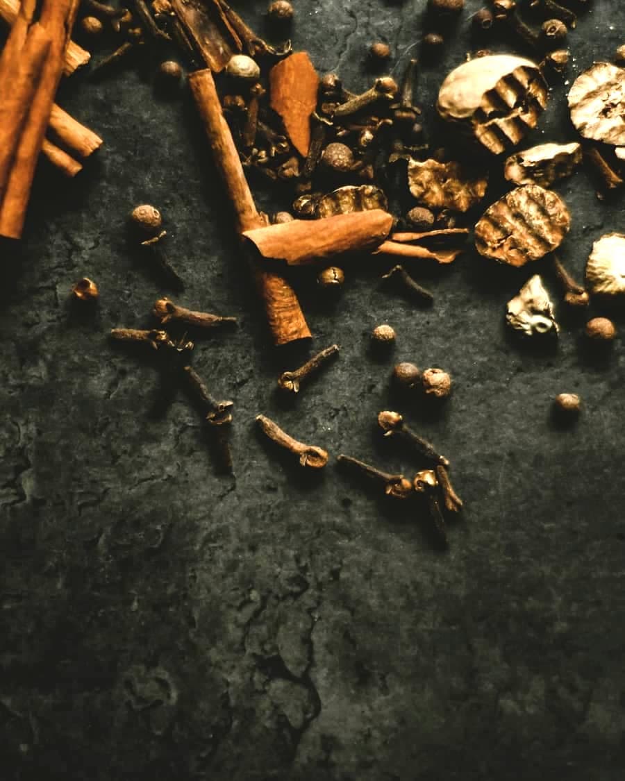 Cinnamon, cloves and nutmeg scattered on a dark stone surface